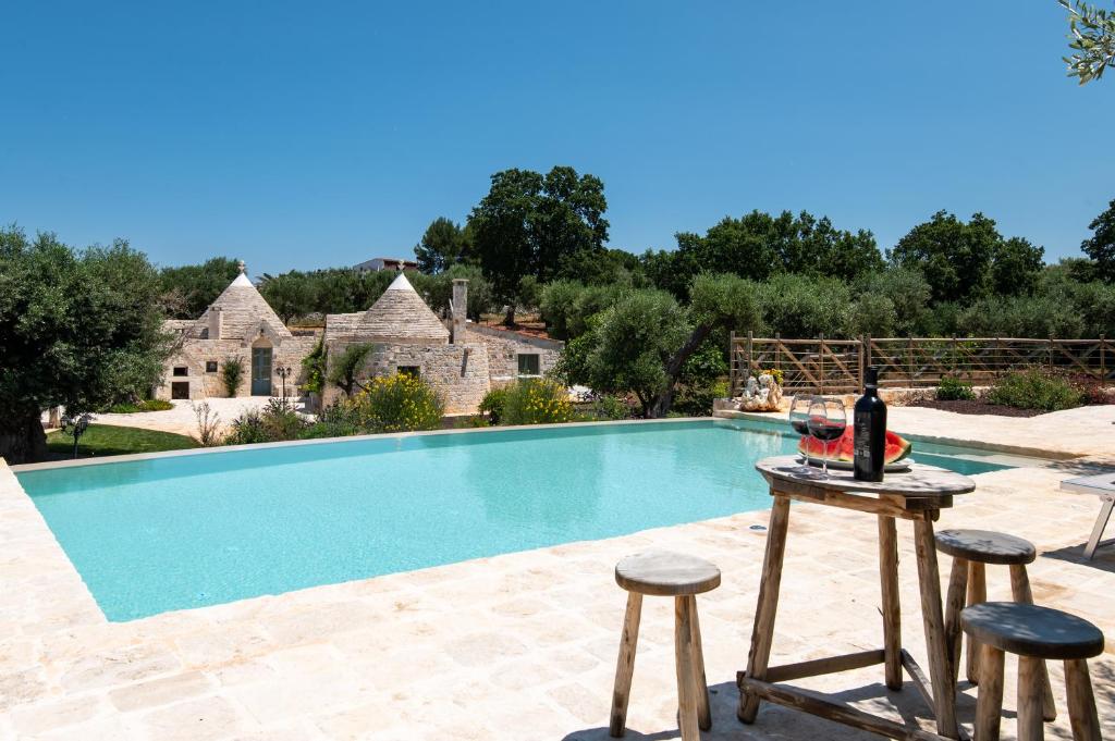 - une table avec une bouteille de vin à côté de la piscine dans l'établissement Trulli Ericla Resort, à Castellana Grotte