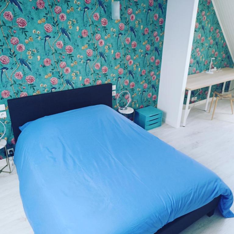 a bedroom with a blue bed with a floral wallpaper at La Casa in Saint-Brieuc