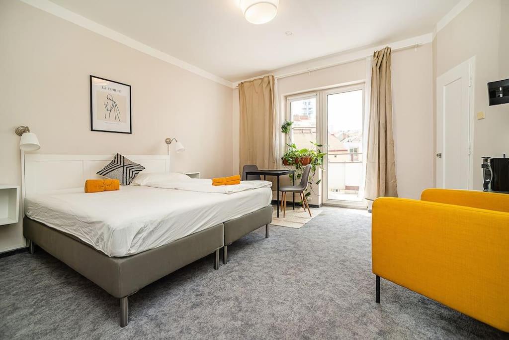 a bedroom with a bed and a yellow couch at Cosy studio with terrace by tram in Prague