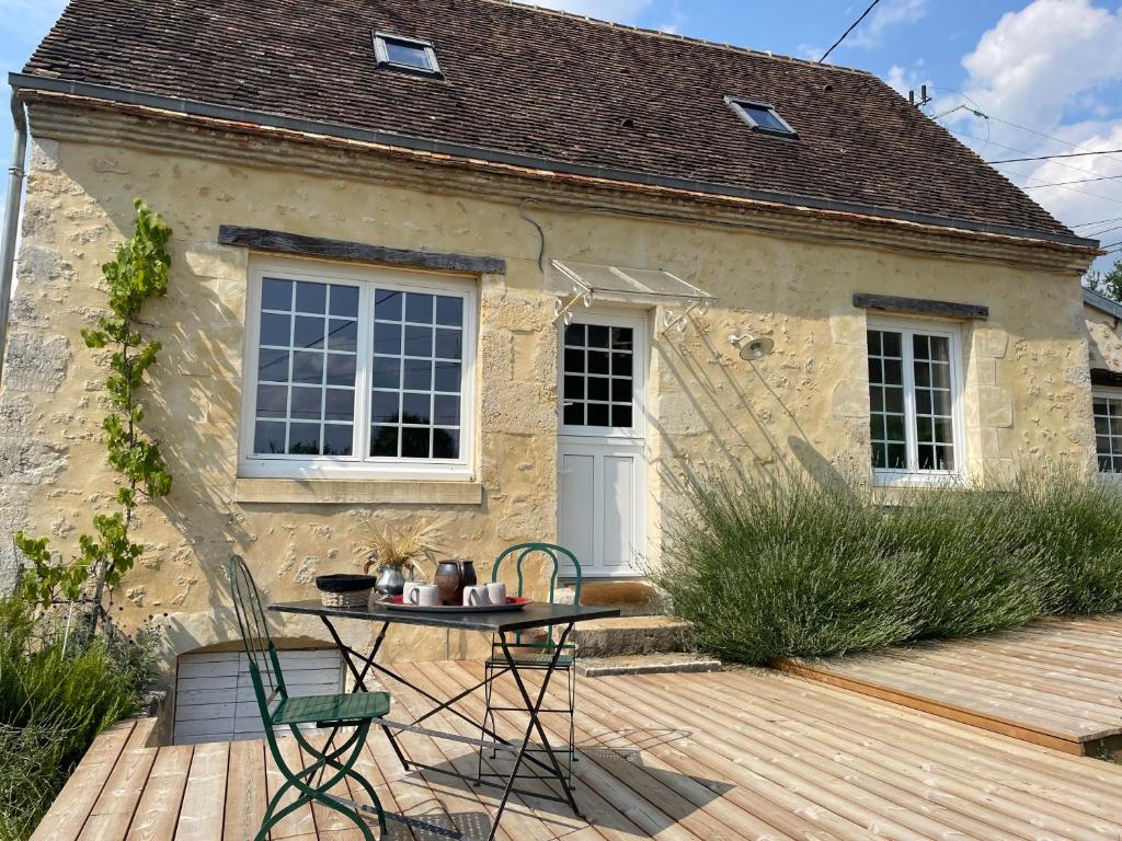 a small stone house with a table and chairs on a deck at Loue charmante maison de vacances à 10 mns de Bellême (61) 