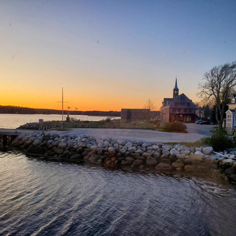 a river with a stone retaining wall and a church at Albert's in Shelburne