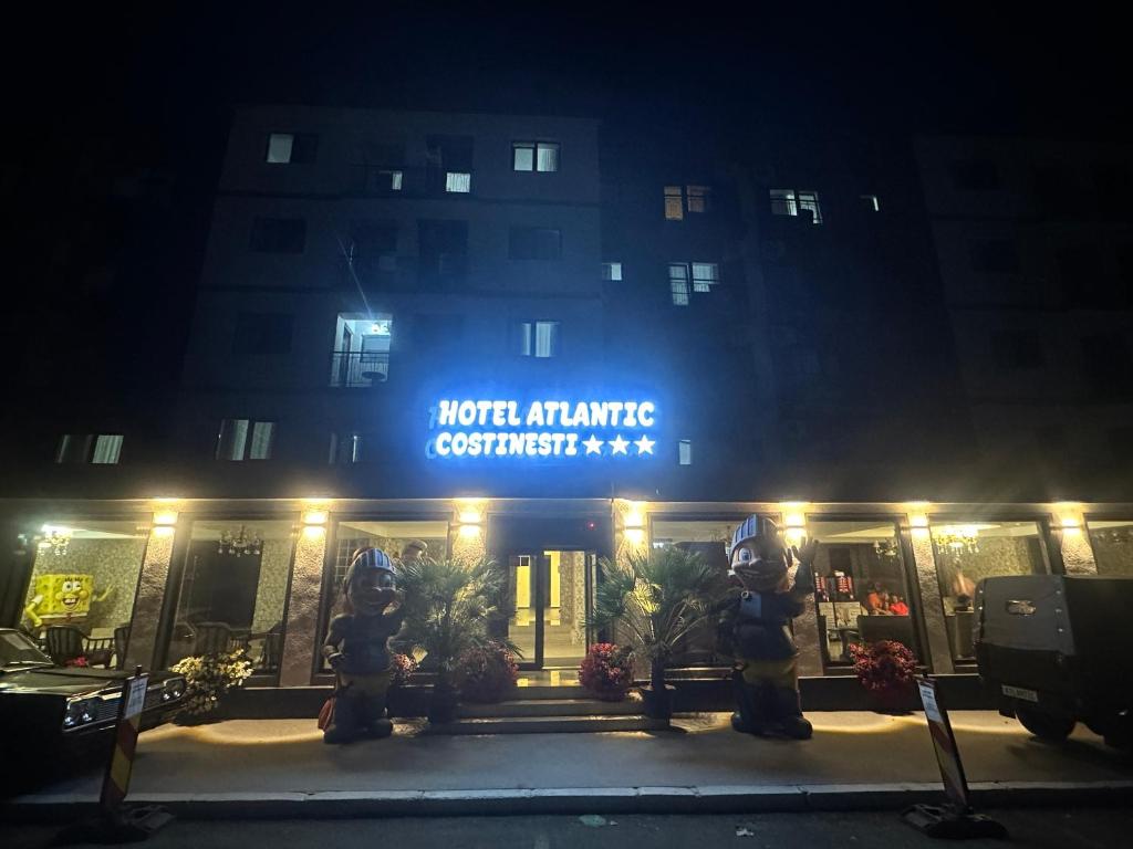 un hotel de noche con dos bocas de incendios frente a él en Hotel Atlantic Costinesti, en Costinesti