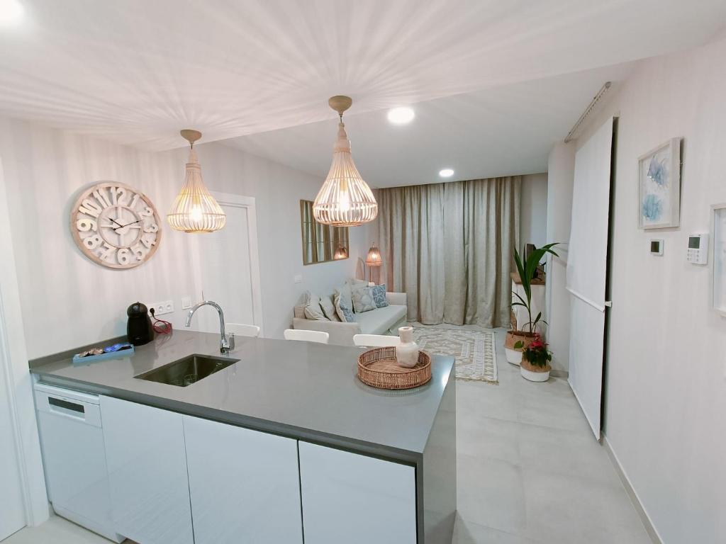 a white kitchen with a sink and a living room at Malvagon Isla Canela los flamencos in Isla Canela