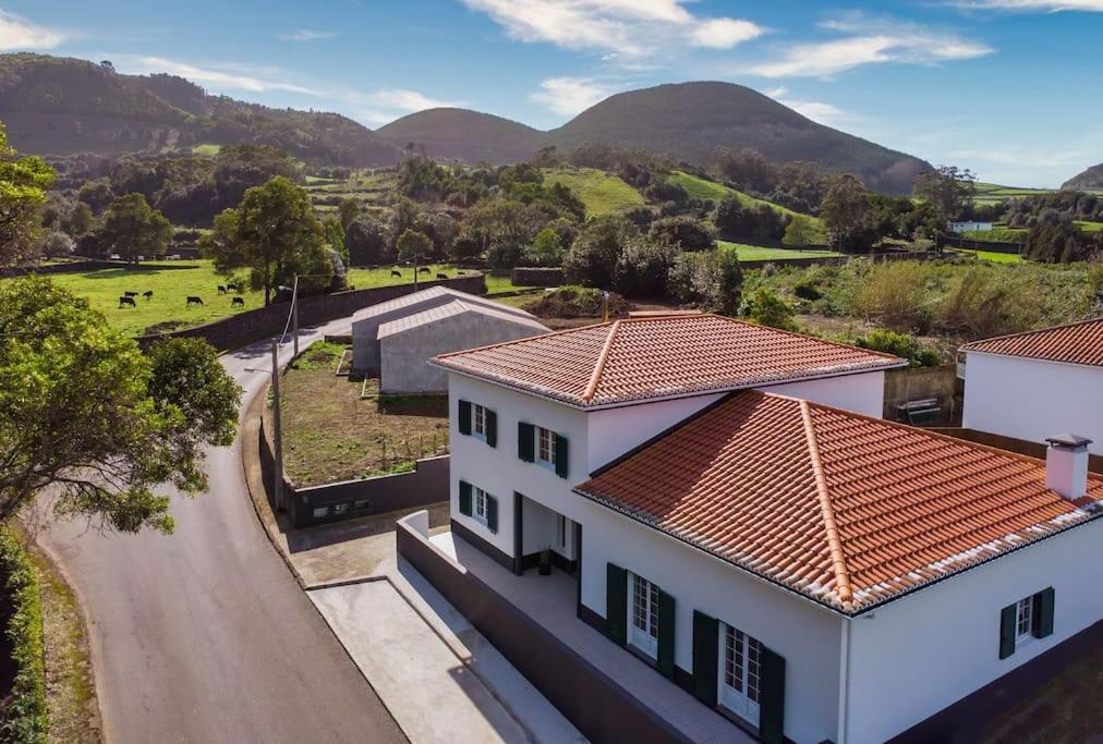 una vista aérea de una casa con montañas en el fondo en Batalha Family House, en Fenais da Luz