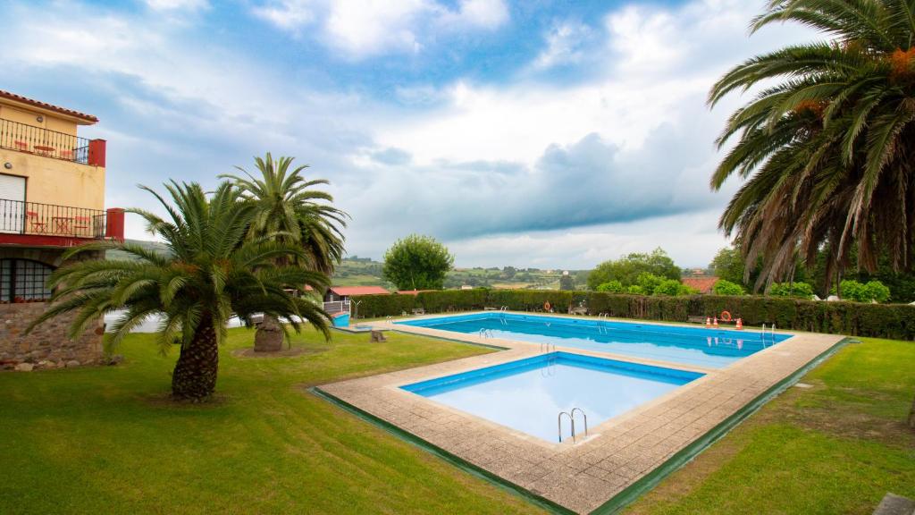 a swimming pool in a yard with palm trees at Resort Camping Santillana del Mar in Santillana del Mar