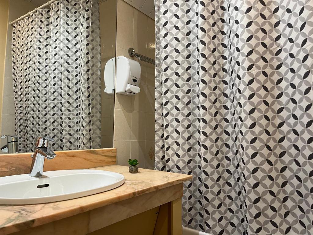 a bathroom with a sink and a shower curtain at Hôtel Le Lacuzon in Moirans-en-Montagne