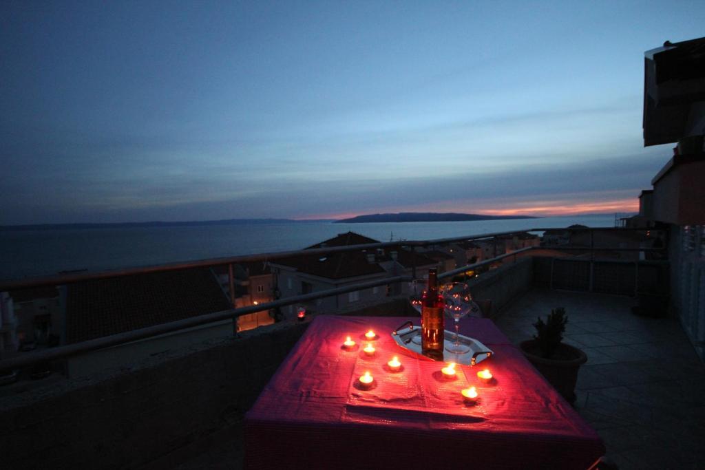 a red table with lights on a balcony at night at Apartments Adriatika in Makarska