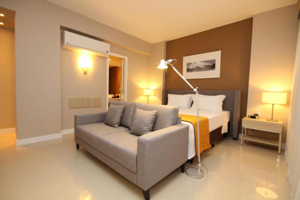 um quarto com um sofá, uma cama e um candeeiro em Linda suíte de hotel Harry no Rio de Janeiro