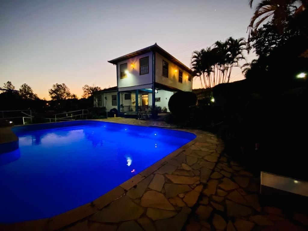 une piscine bleue en face d'une maison dans l'établissement Pousada Casarão De Minas, à São Lourenço