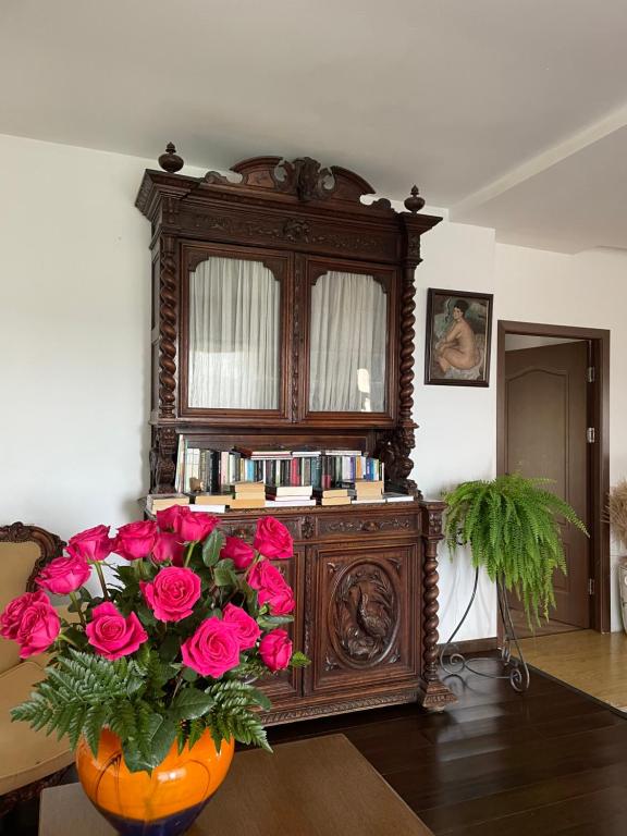a large wooden cabinet with a vase of pink roses at Conacul Paloși in Horezu