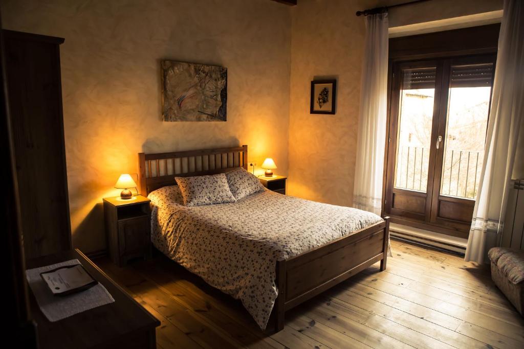una camera da letto con un letto, due lampade e una finestra di La Plazuela a Morcuera