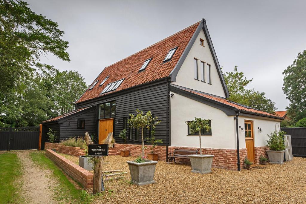 uma pequena casa a preto e branco com um telhado em The Threshing Barn em Forncett Saint Mary