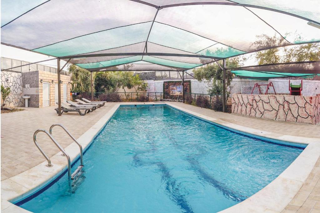 uma piscina com um guarda-chuva sobre ela em ليا شاليه liya chalet em Ash Shāghūr