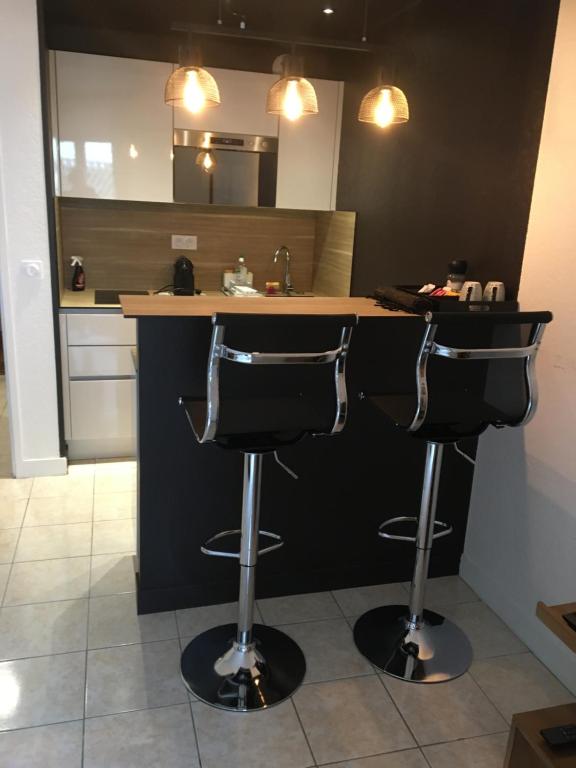 a kitchen with two bar stools in front of a counter at Hyper centre Deauville in Deauville