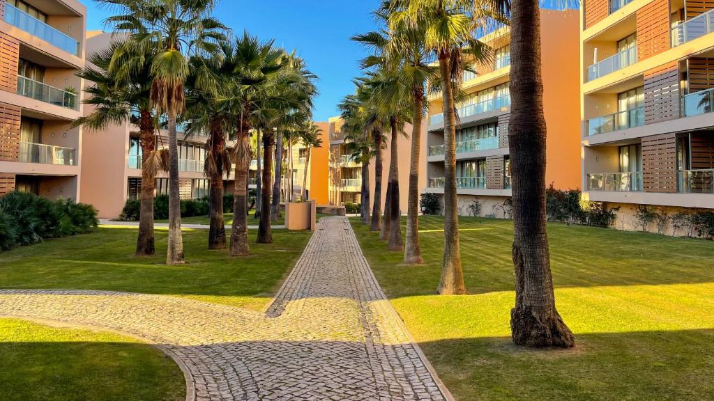 a walkway in front of a building with palm trees at Herdade dos Salgados,T3 8C-0C, Vila das Lagoas in Albufeira