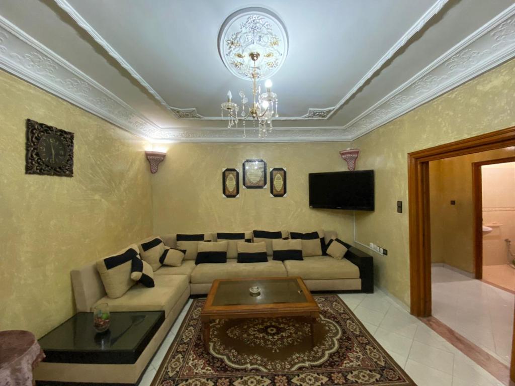 a living room with a couch and a chandelier at ELFA APPARTEMENTS Familiaux in Agadir