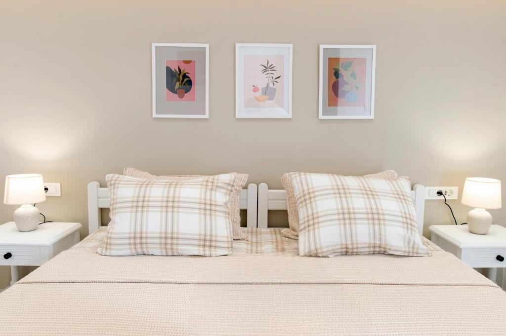 a bedroom with a white bed with two white tables and three paintings at Kos Olympia Apartment superior in Kos Town