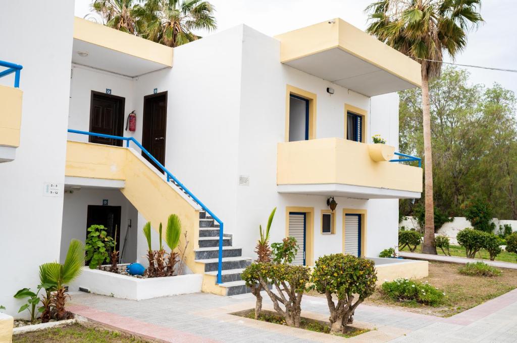 a white house with blue stairs and palm trees at Kos Olympia Apartment superior at Lambi Beach in Kos Town