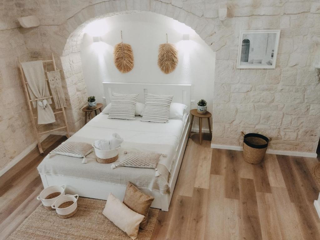 ein Schlafzimmer mit einem weißen Bett und einer Steinmauer in der Unterkunft Casa De Amicis in Sammichele di Bari
