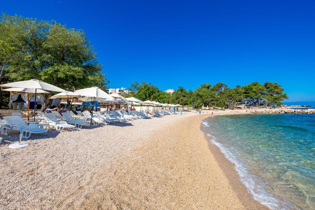 a beach with chairs and umbrellas and the ocean at Blue Waves Resort in Malinska