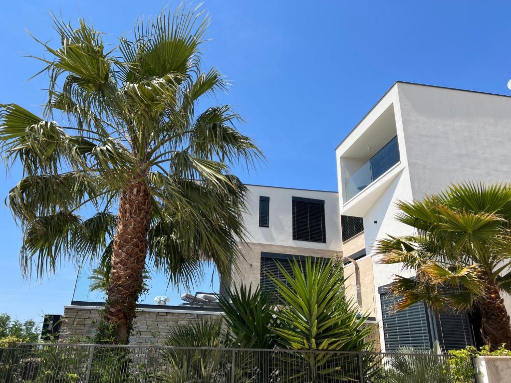 a white building with palm trees in front of it at Villa Night Pearl in Trogir