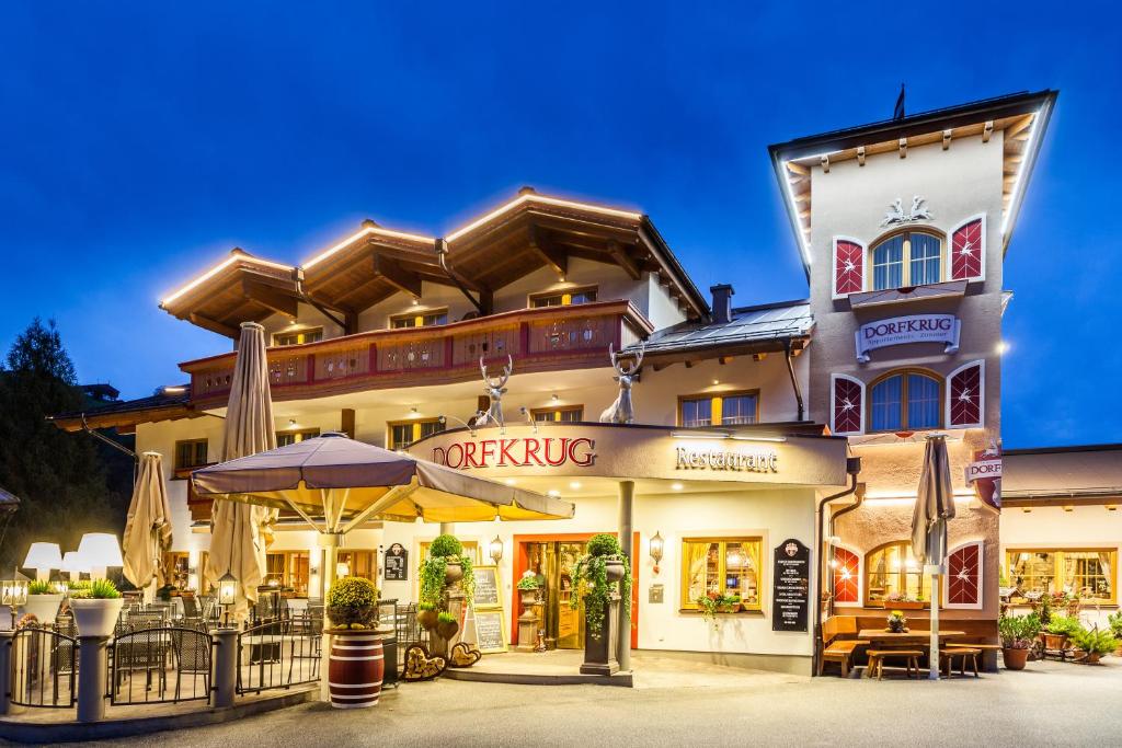 a large building with an umbrella in front of it at Dorfkrug Kaprun inklusive Summercard and in winter Tauern Spa Kaprun in Kaprun