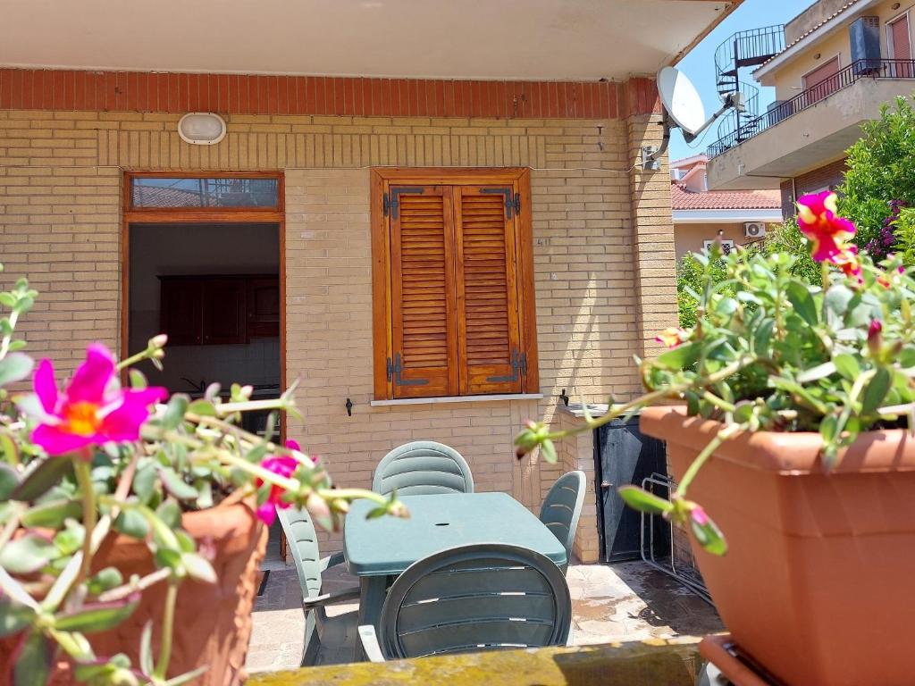 un patio con tavolo, sedie e fiori di casa delle margherite Ladispoli a Ladispoli