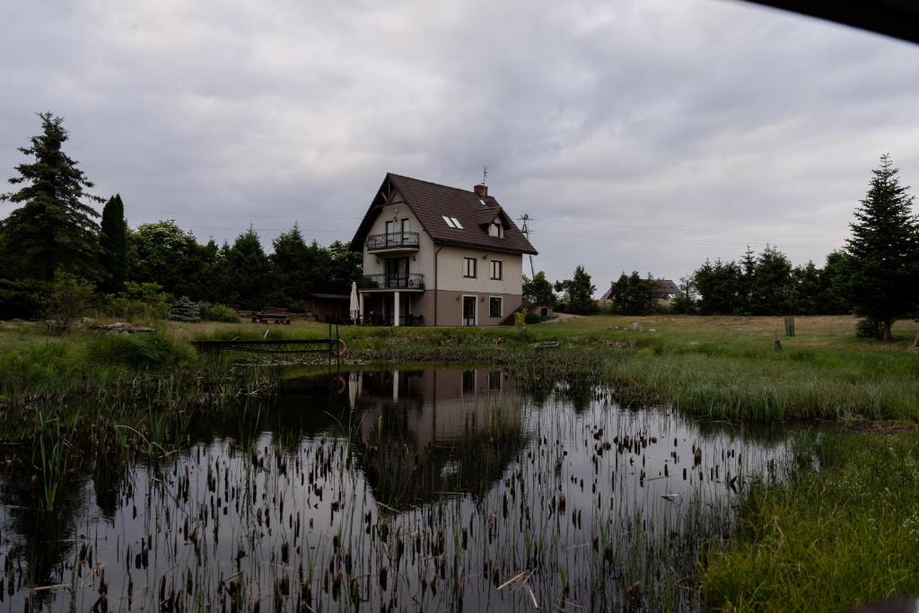 una casa sentada junto a un gran cuerpo de agua en Willa nad stawem, en Mezowo