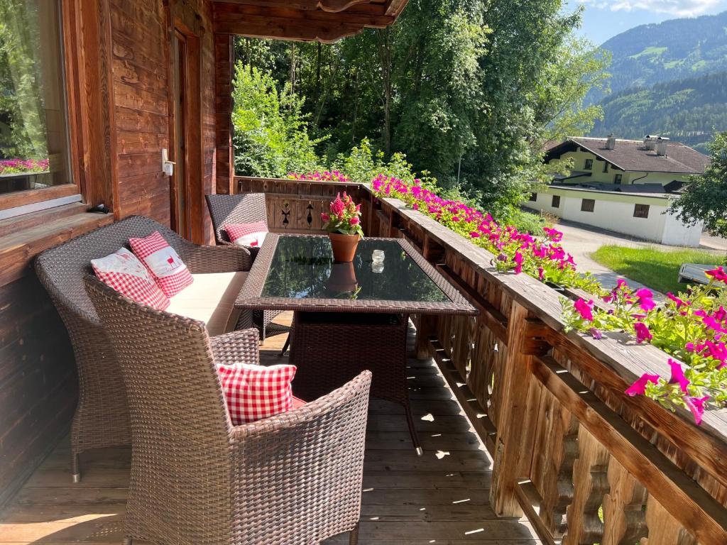 eine Außenterrasse mit einem Tisch, Stühlen und Blumen in der Unterkunft Ferienwohnung Platzhirsch Panorama View Balkon, Gartensauna, Garten, Grillplatz in Stumm