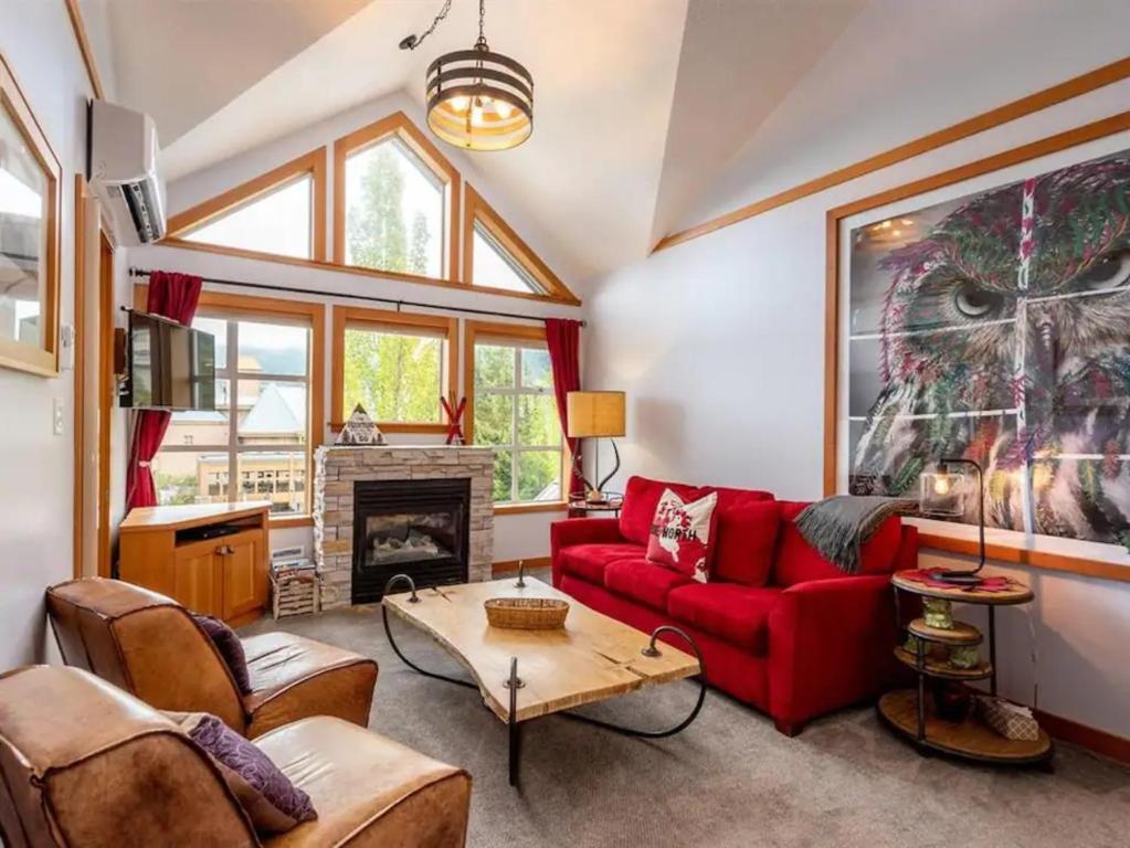 a living room with a red couch and a fireplace at Stunning 2BR w Pool, Hot Tub Walk to everything! in Whistler