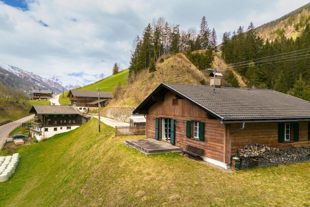 una pequeña casa de madera en una colina con césped en Gemütliches Ferienhaus im Defereggental, 