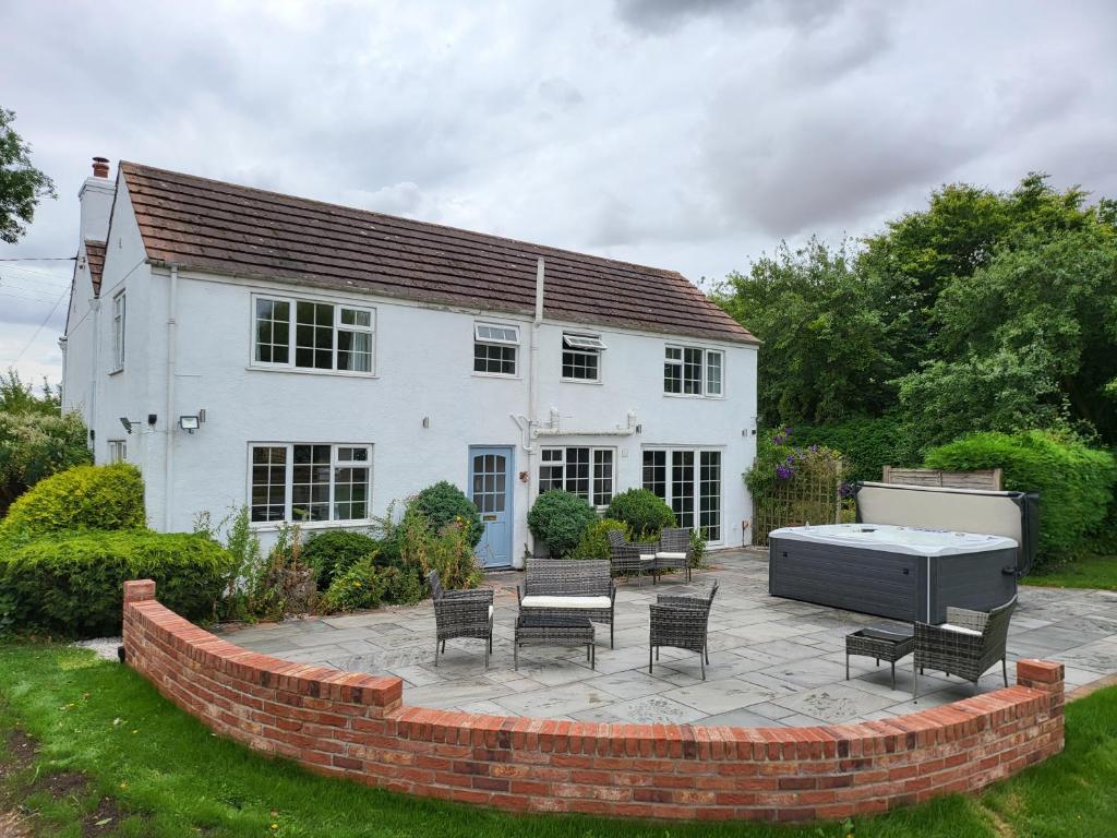 a white house with a patio with chairs and a table at Holly Cottage in Lincoln