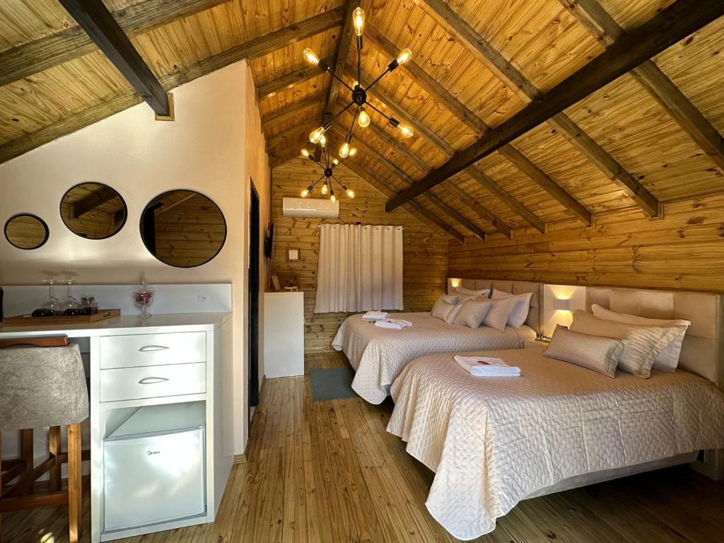 a bedroom with two beds in a room with wooden ceilings at Cabanas Charme da Serra in Cambara do Sul