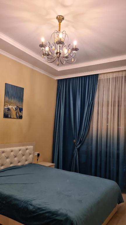 Un dormitorio con una cama azul y una lámpara de araña. en Иссык-Куль Кыргызстан, коттедж ЦО Палм Бич en Chok-Tal