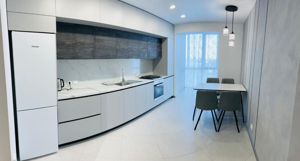 a kitchen with white cabinets and a table and chairs at VIP Апартаменти подобово in Lutsk