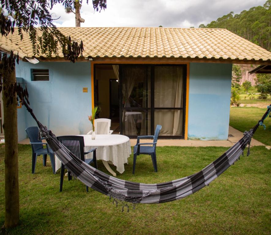 a hammock in front of a house with a table and chairs at Vila ACONCHEGO AZUL 2 in Aracê