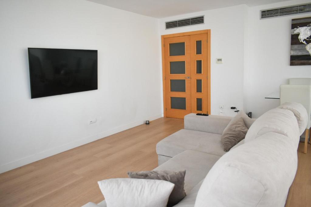 a white living room with a white couch and a tv at Magnifique Apartament Valencia in Valencia