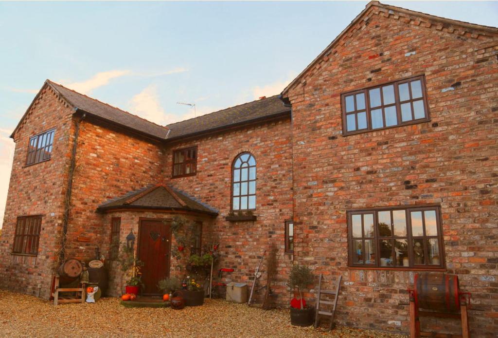 a large brick building with a door and windows at Bumbleberry Cottage in Gresford