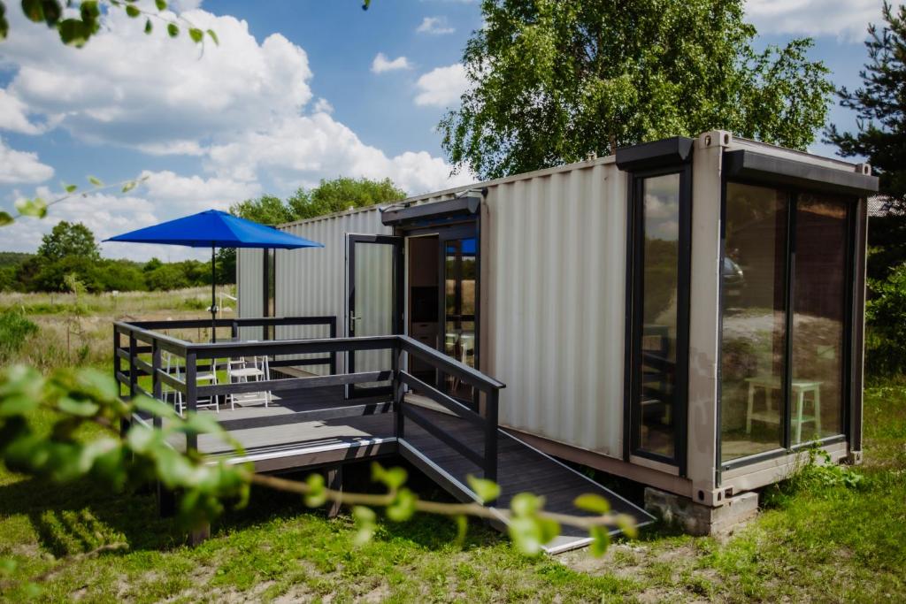 a tiny house with a deck and an umbrella at Kontenery Kapalica 