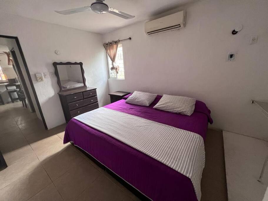 Un dormitorio con una cama morada y blanca y un espejo en Departamento Canek 1 en Mérida