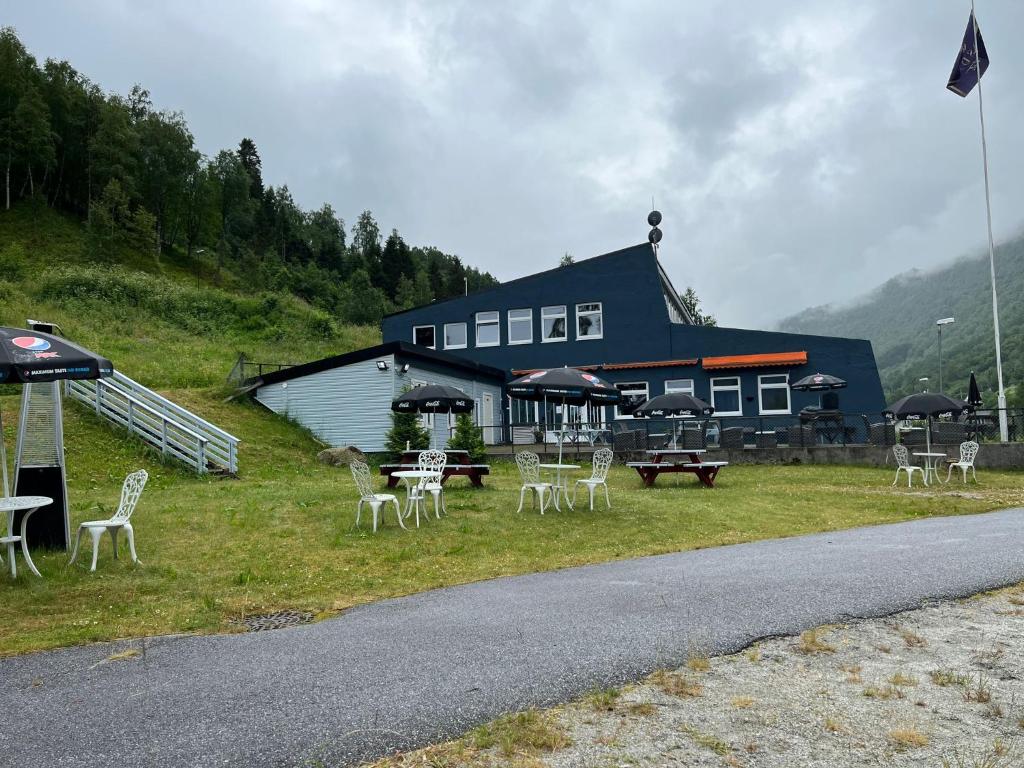 un edificio con mesas y sillas al lado de una carretera en Eidsdal Rest House en Eidsdal