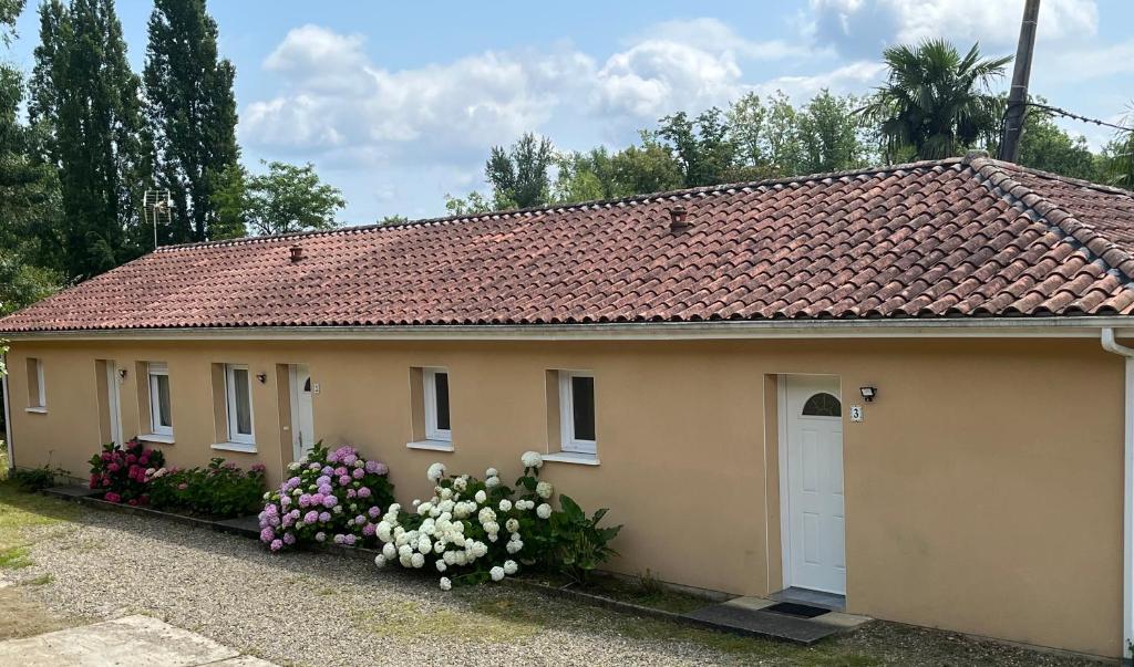une petite maison avec des fleurs devant elle dans l'établissement LES IRIS 1 T2 45m2 à 200m des thermes, à Eugénie-les-Bains