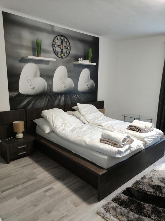 1 dormitorio con 1 cama con almohadas blancas y reloj en Freedom-Fehérvár apartman en Székesfehérvár
