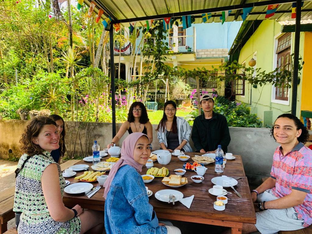 a group of people sitting around a wooden table at Rock View Hostel Ella in Ella