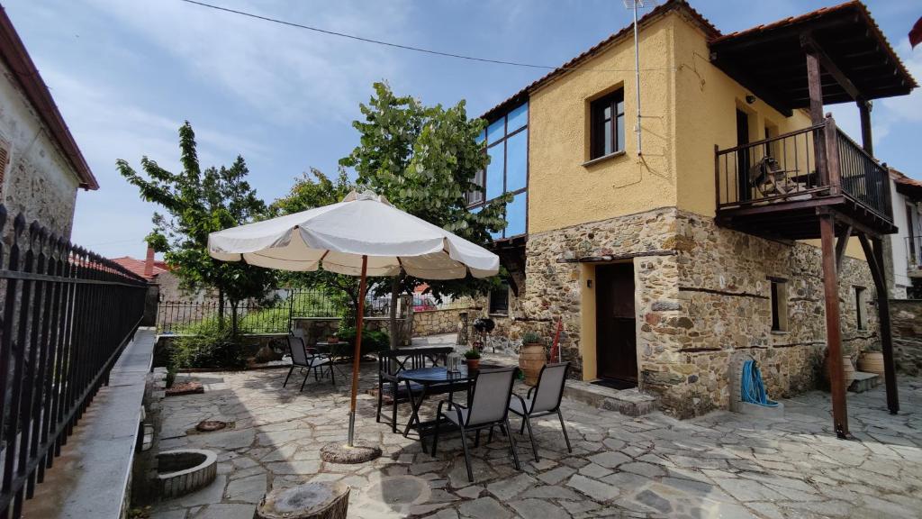 eine Terrasse mit einem Tisch und einem Sonnenschirm vor einem Gebäude in der Unterkunft The Stone House in Halkidiki in Vávdhos
