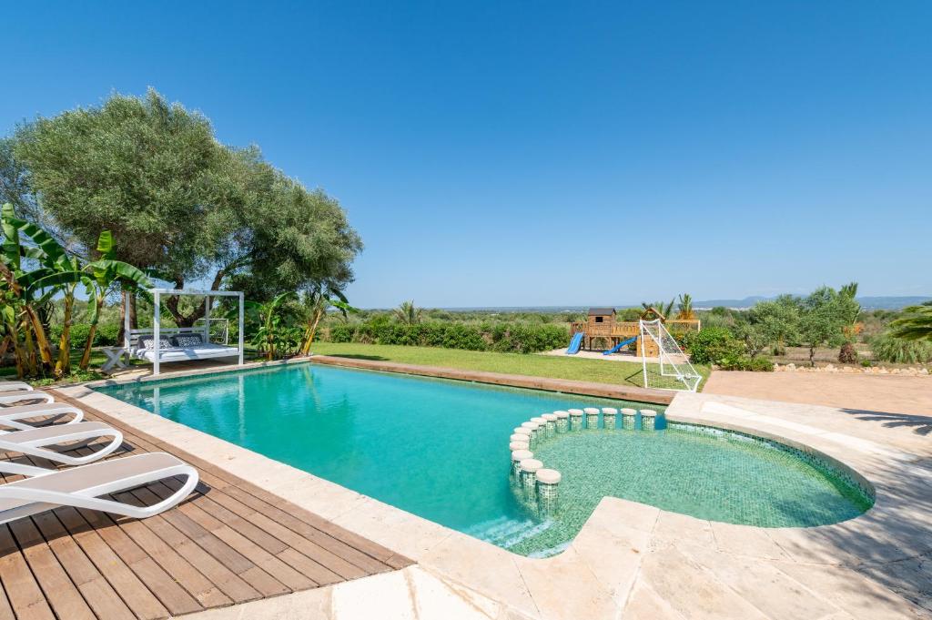 a swimming pool with lounge chairs next to a resort at Finca Es Figueral in Campos