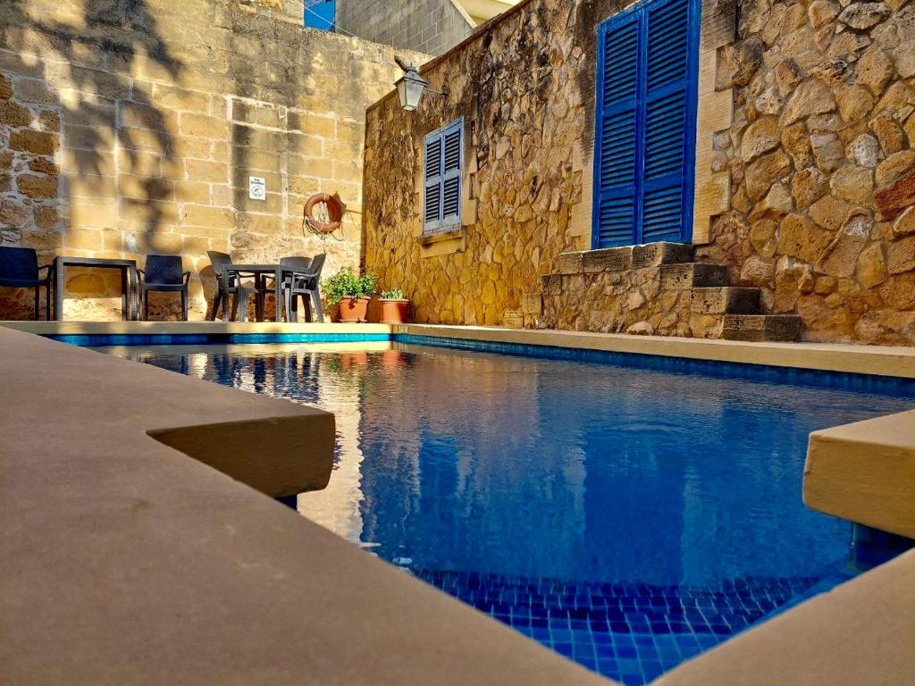 a swimming pool in a house with a stone wall at MJ Farmhouse B&B in Xagħra