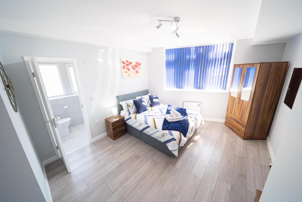 ein Schlafzimmer mit einem Bett mit blauen Kissen in der Unterkunft Stylish Studios with Ensuite, Separate Kitchen, and Prime Location in St Helen in Saint Helens