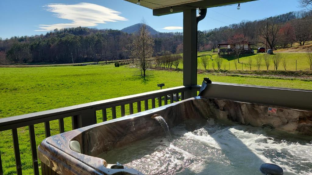 a hot tub on a balcony with a view of a field at Cozy Cottage with Full View of the Mountains! in Blue Ridge
