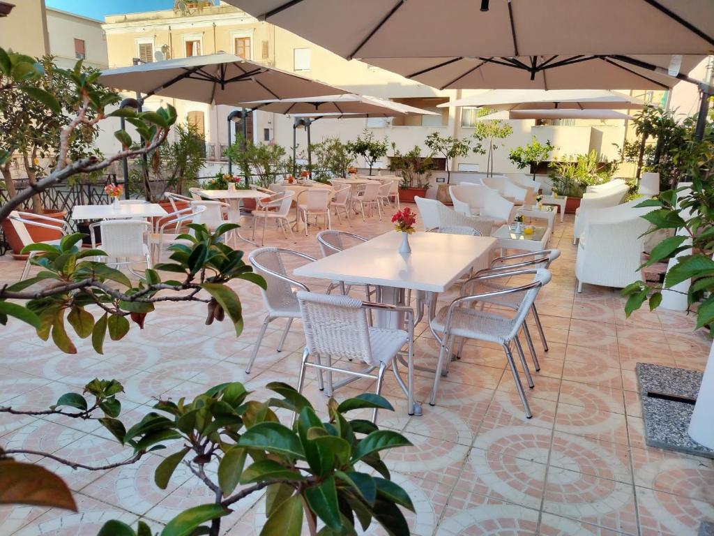 een patio met tafels, stoelen en parasols bij Hotel Trinacria in Palermo